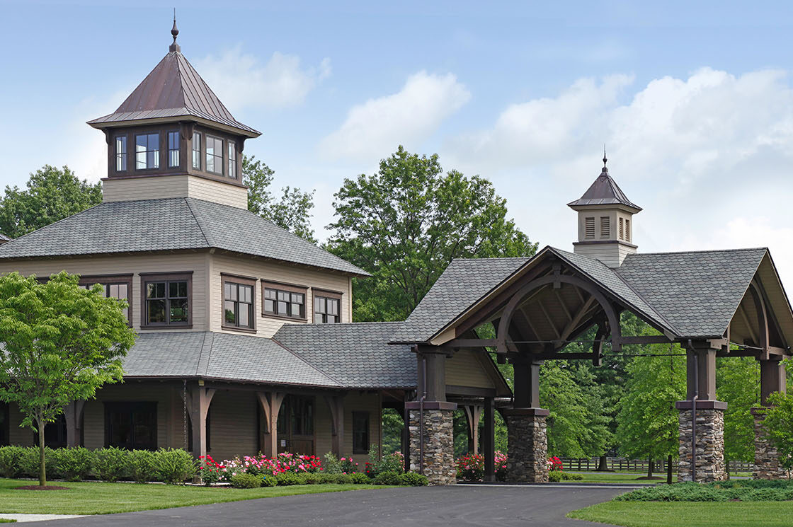 custom equine facility with a drive through overhang on the right which sits beneath a blue sky