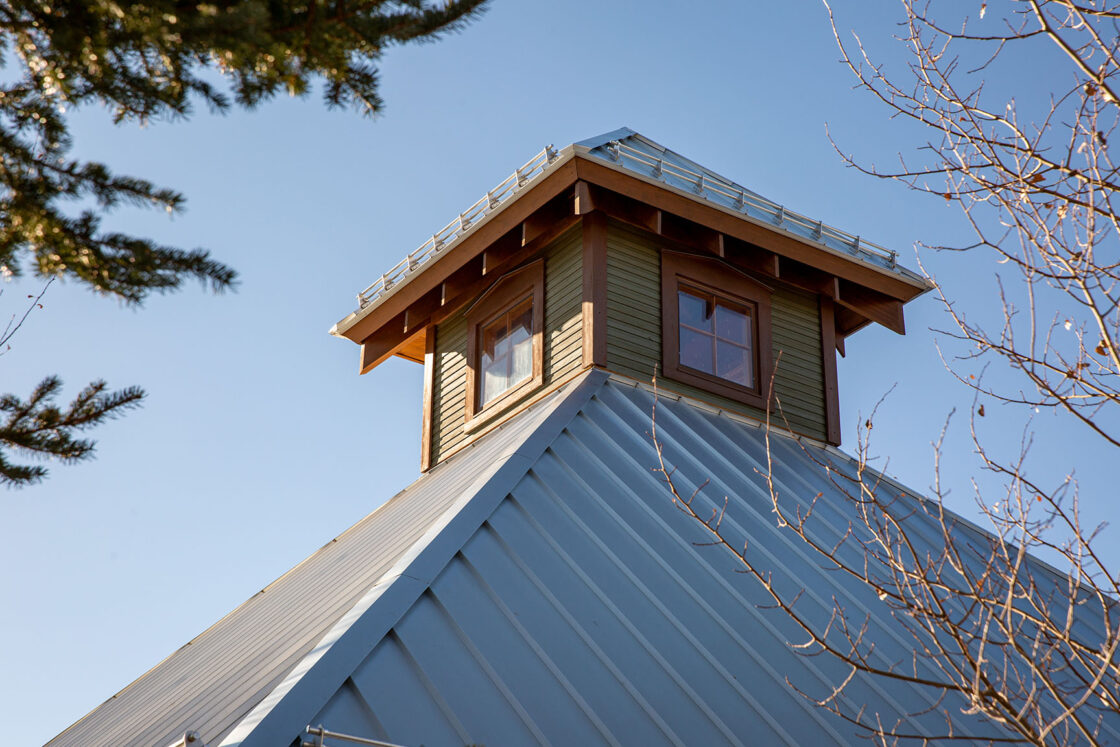 custom garage roof sitting beneath a clear sky with visible tree branches on both sides