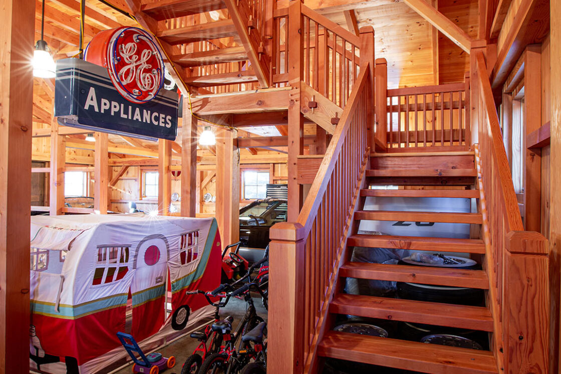 custom wooden staircase sitting beneath an illuminated light fixture with an old ge appliance sign visible to the right which site above a novelty trailer