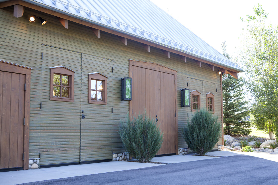 custom built structure with tall dual wooden doors sitting between four windows and two bushes