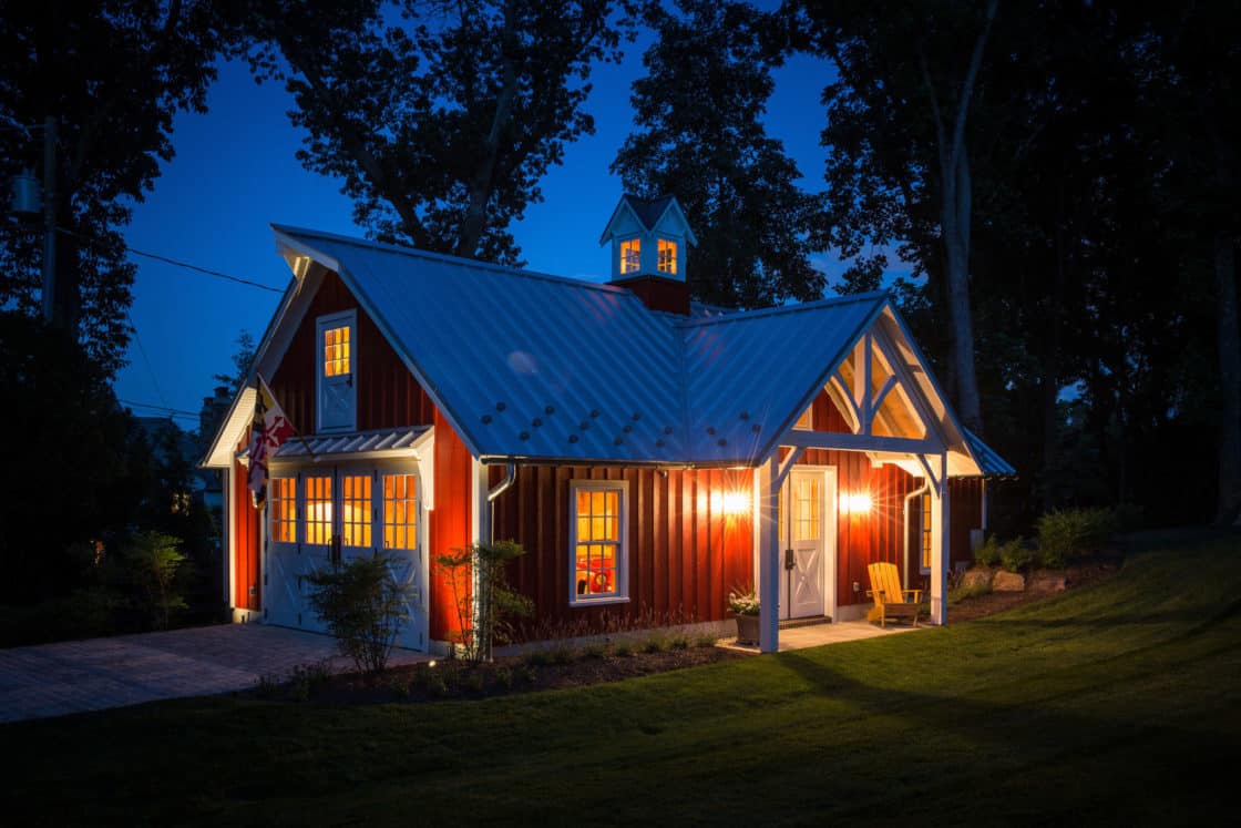 red custom garage sitting beneath the night sky with multiple interior and exterior lights turned on