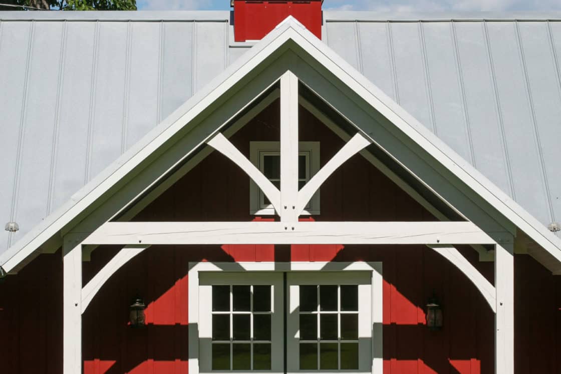 white symmetrical front doors sitting beneath overhand of red custom garage
