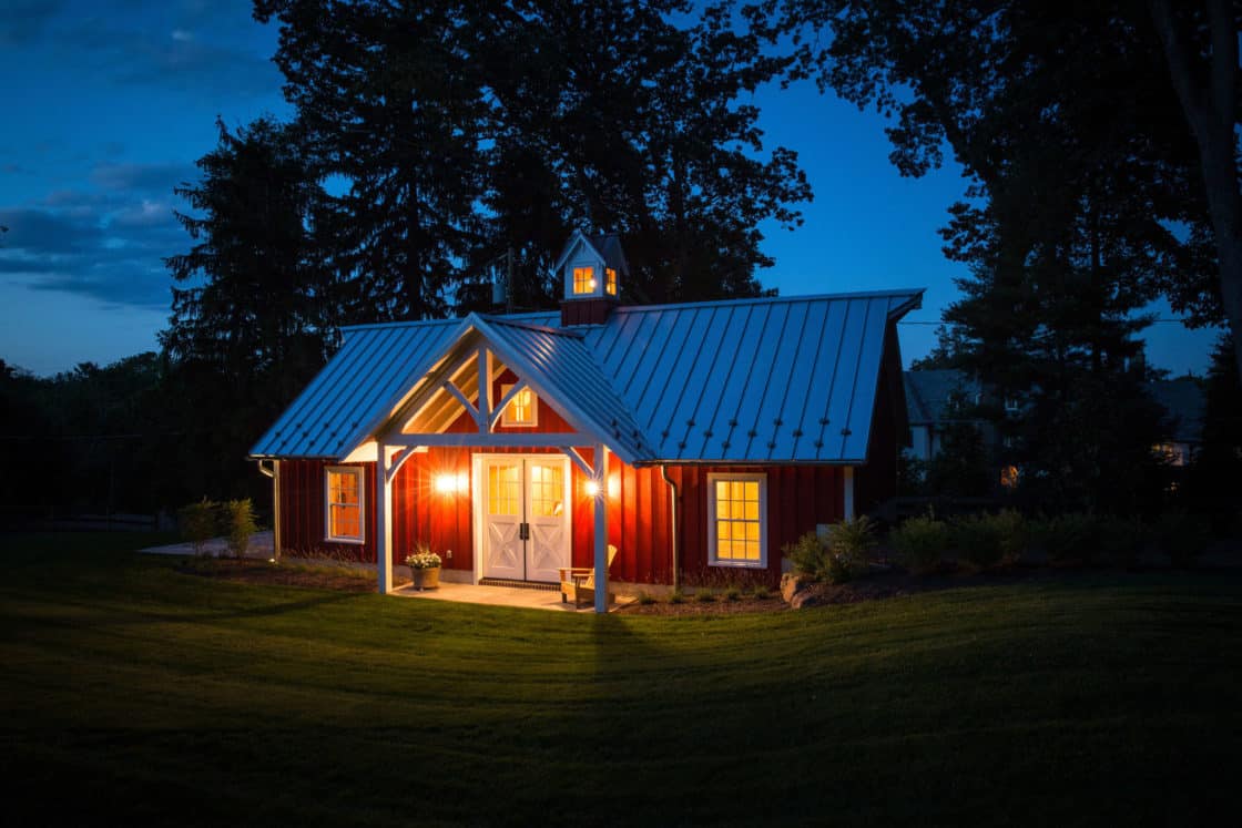 exterior view of custom garage sitting beneath evening sky with exterior lights turned on