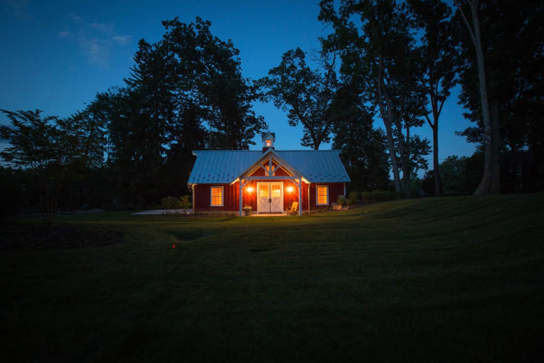 landscape view of custom garage sitting in field in the middle of the night