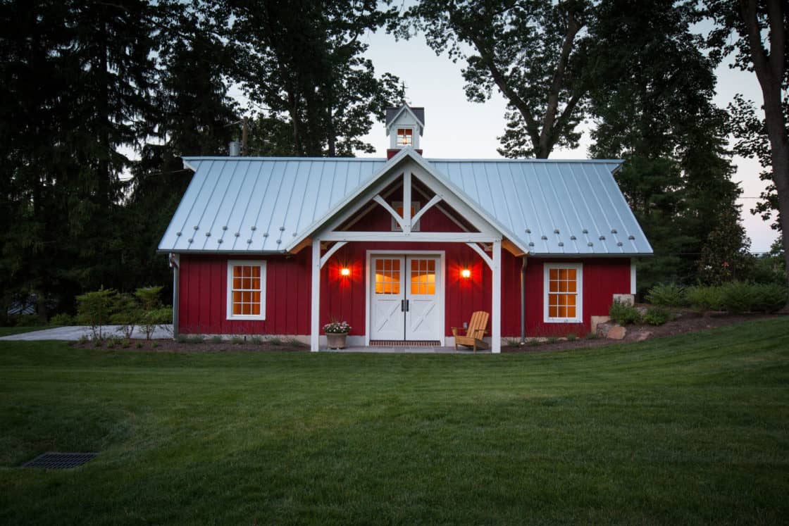 side view of red custom garage with white doors and metal roof