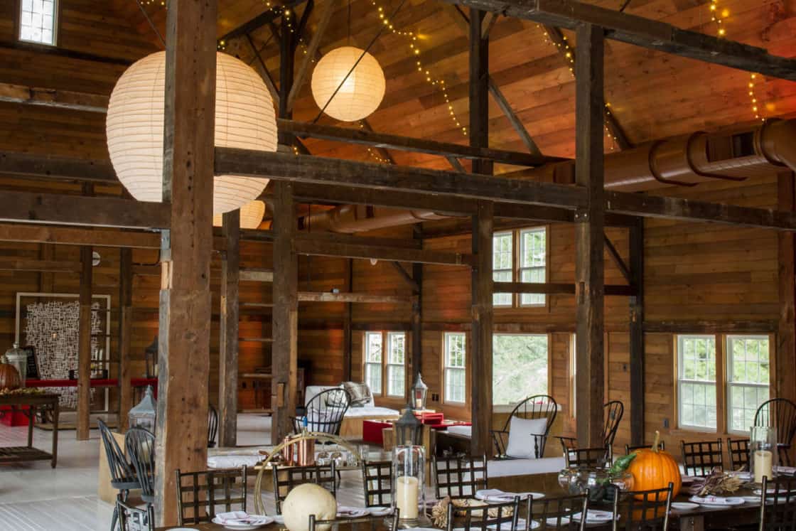 A room with wooden beams and tables and chairs, perfect for a cozy party barn or adding rustic charm to a luxury home.