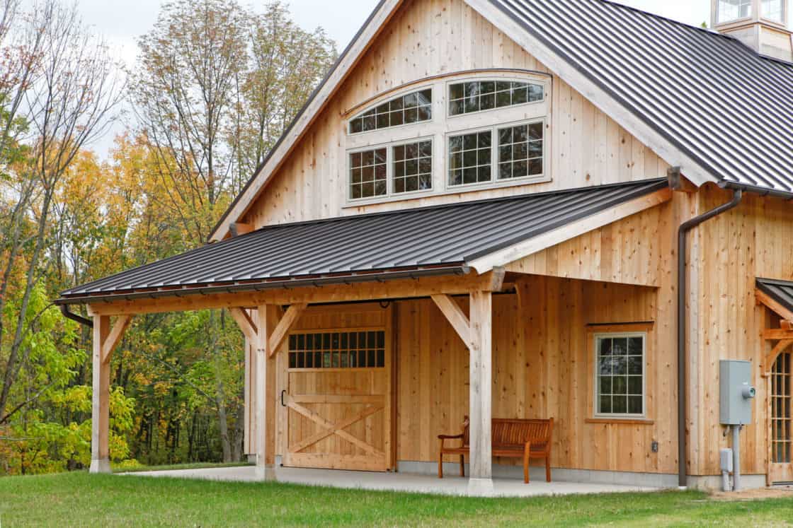 custom garage overhang with green grass in front and wooded area in back