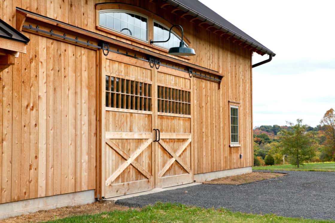 large symmetrical barn doors with black top driveway in front of it