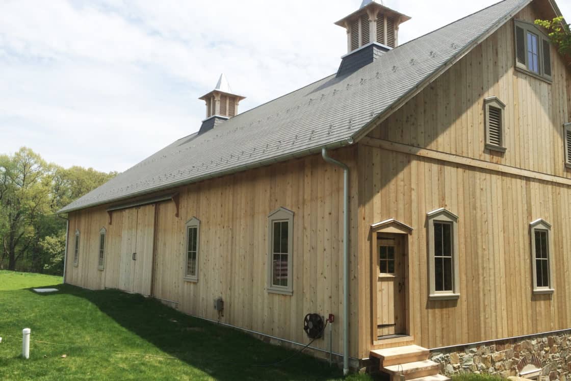 corner view of wooden bank barn with view of two matching cupolas on roof