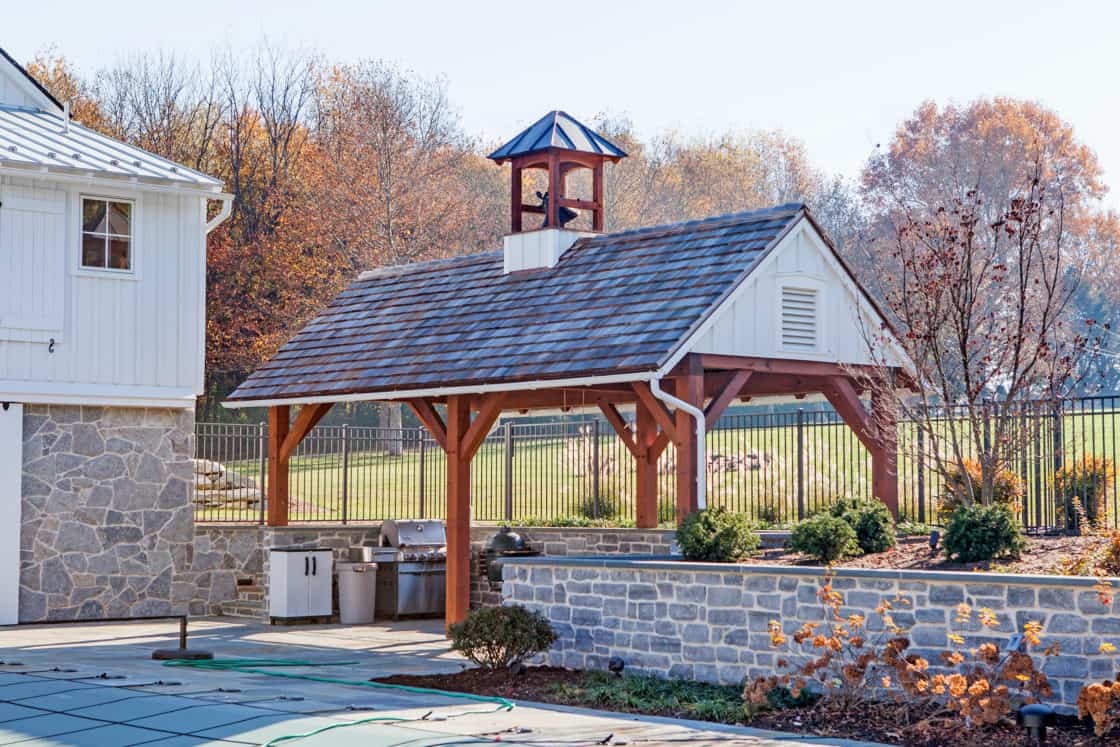 outdoor pavilion with bell on roof with smoker and grill beneath it