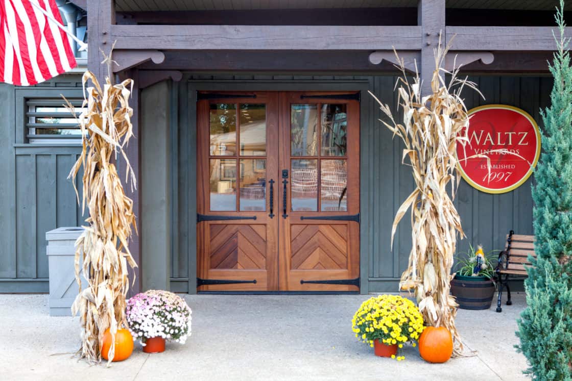 two symmetrical wooden doors sitting behind timber frame beams with fall decorations