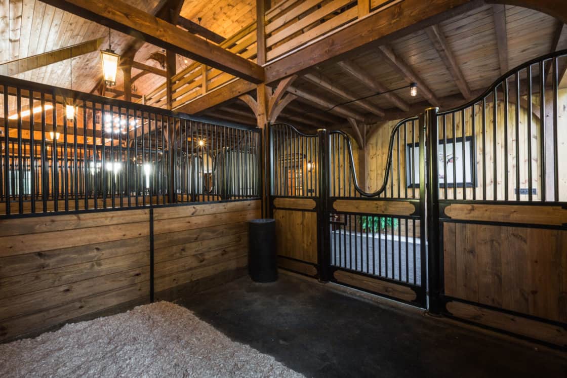 A horse stable with a black gate, reminiscent of a classic bank barn.
