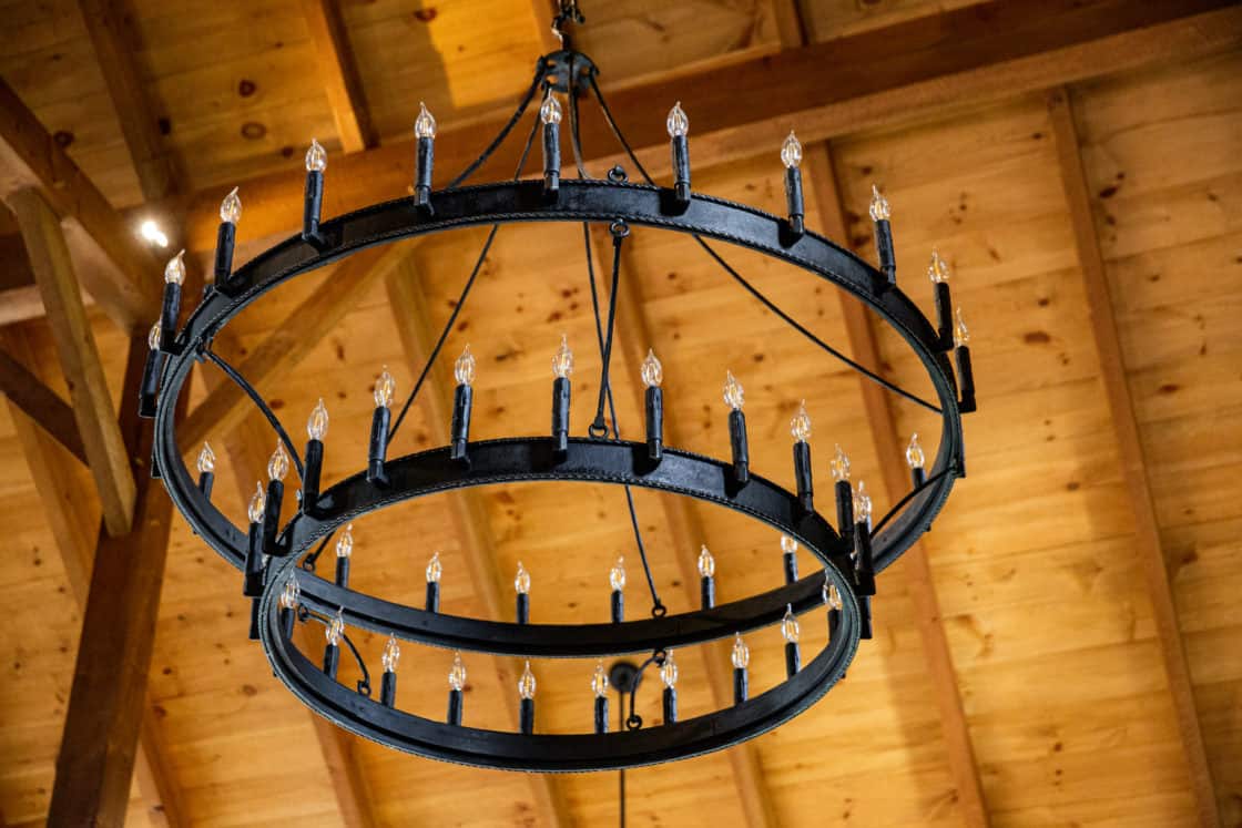 circular light fixture inside party barn handing beneath wood ceiling