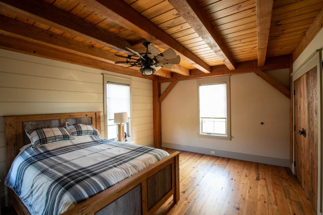 bedroom inside party barn with hardwood floor and newly made bed with plaid blankets