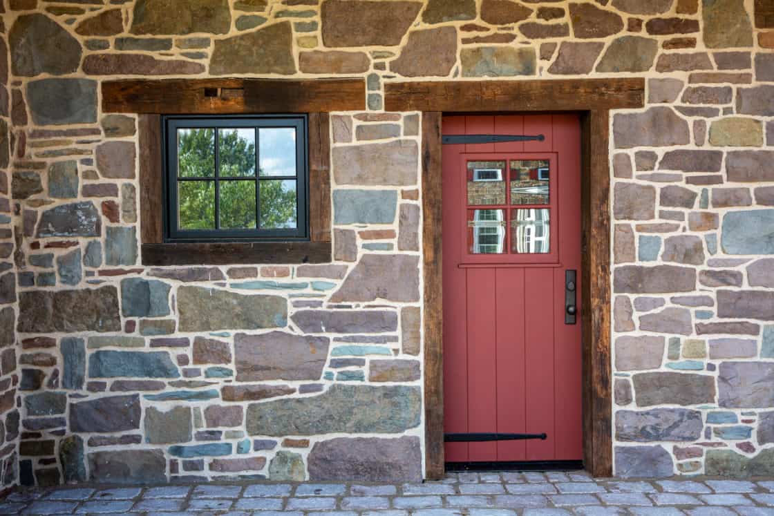 single red door and window on first floor of party barn