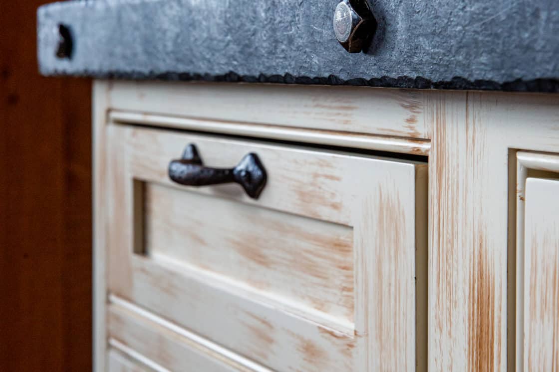 close up view of wood kitchen cabinet with black metal piece on top
