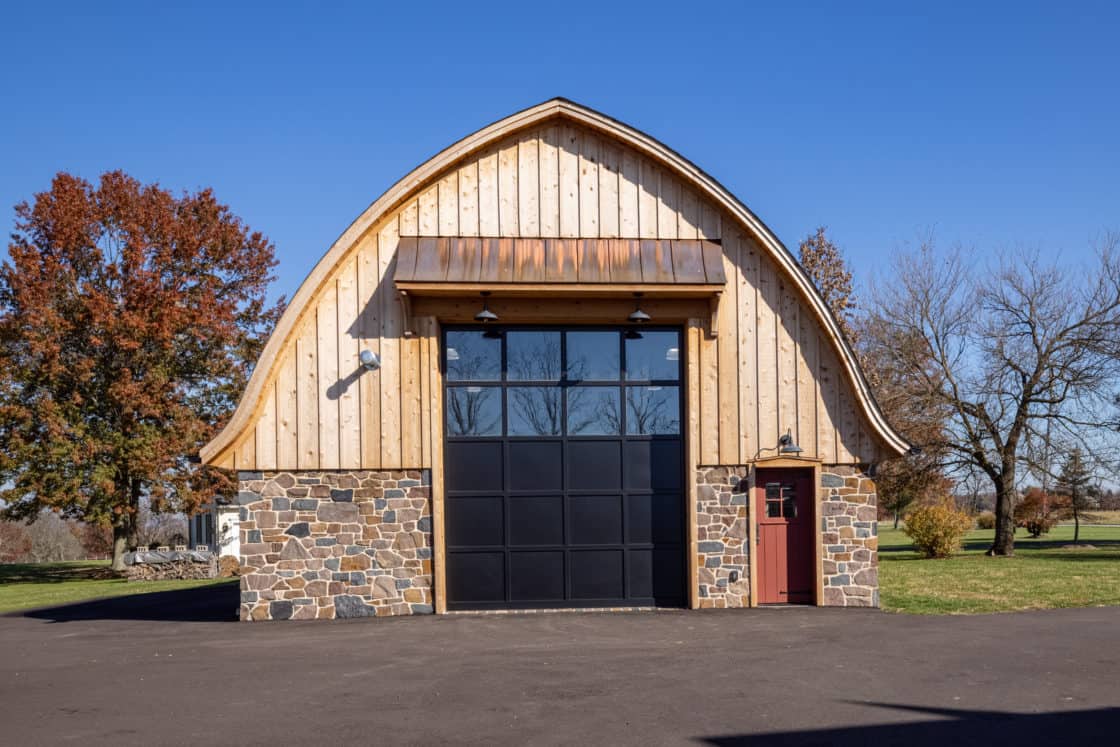 front view of custom built garage with closed front door sitting beneath blue sky