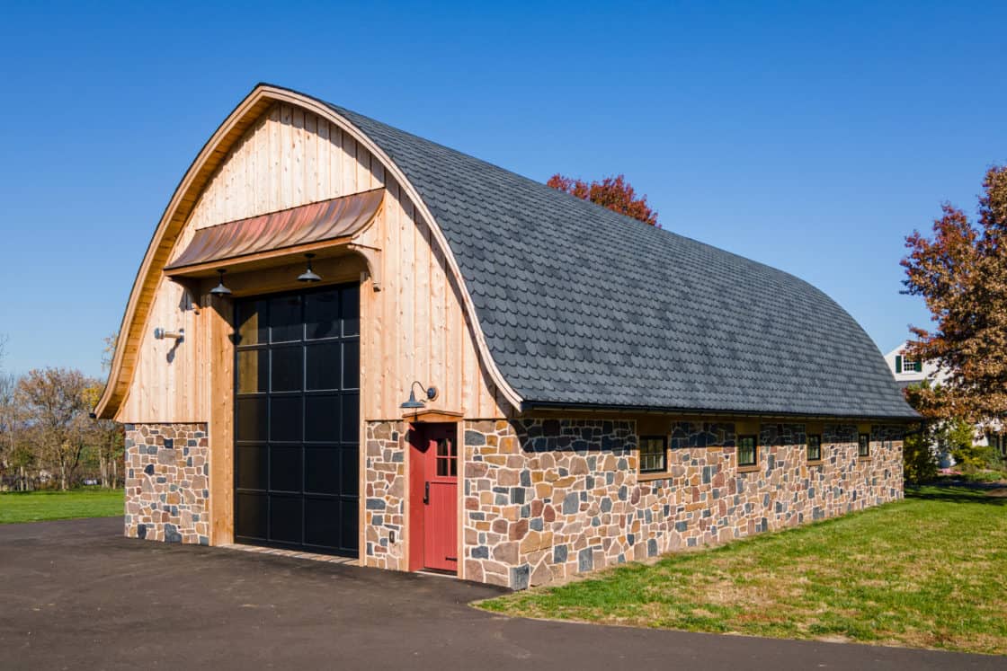 quonset hut bus barn with shingle roof and stone lower siding