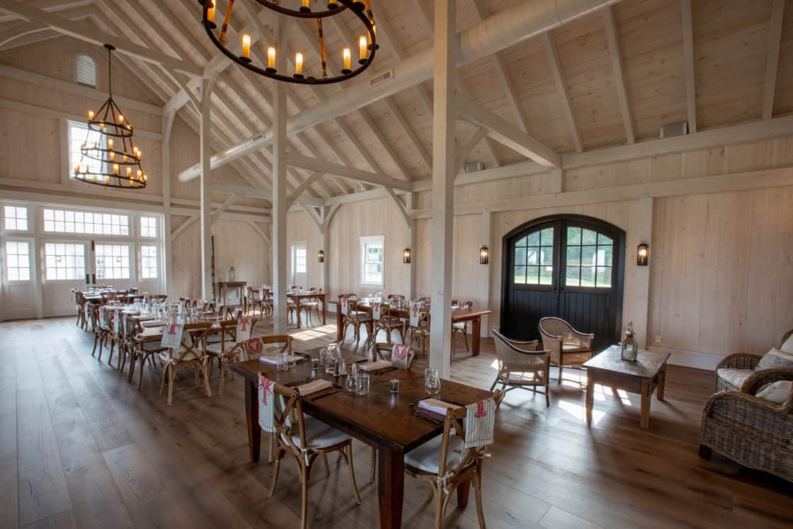multiple wood tables and chairs sitting inside large room in chester county party barn