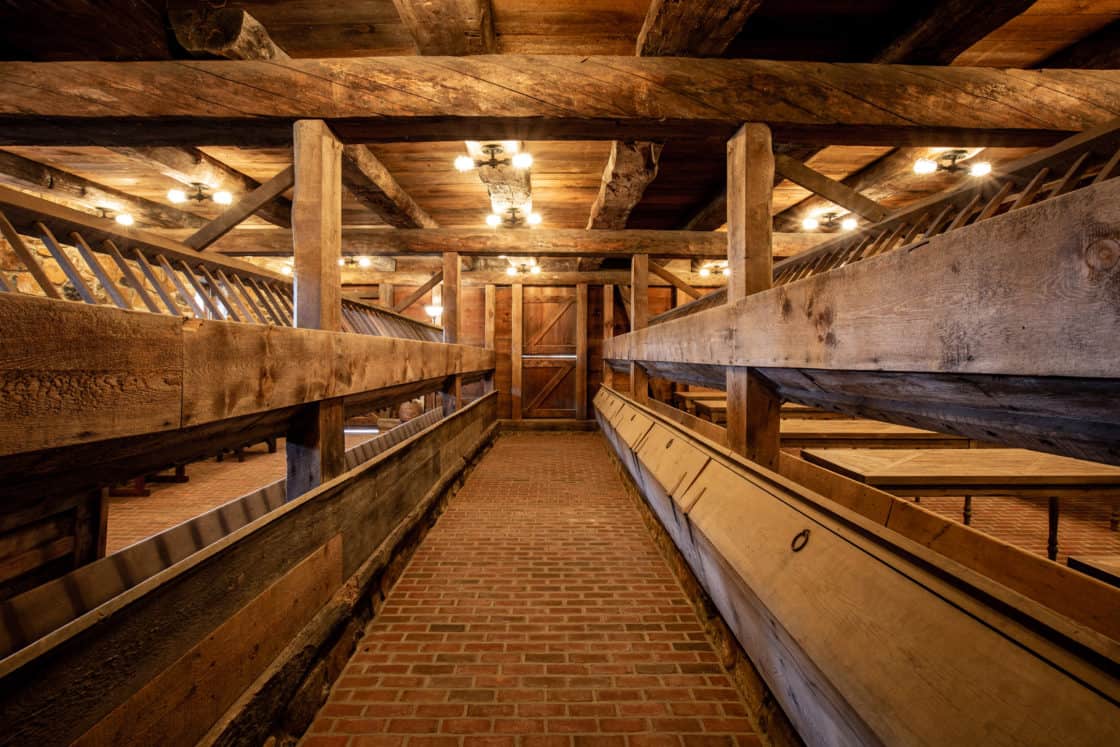 interior of restored barn with brick flooring and wood beams throughout the ceiling