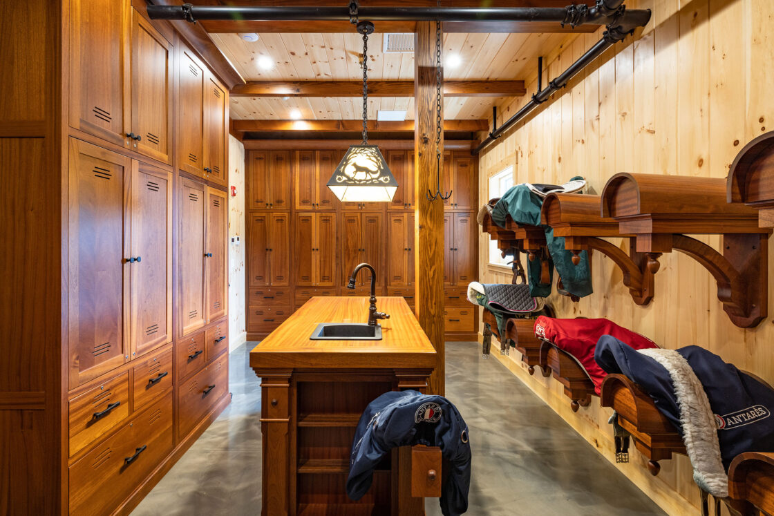 tack room with custom built wooden lockers sitting on the left and rear portion of the view while a wooden island sits between them