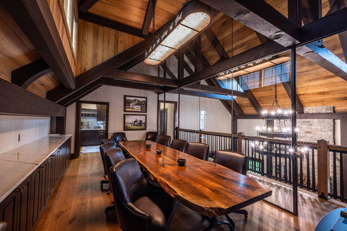 long custom meeting table surrounded by ten leather swivel chairs which sit beneath a hanging light fixture