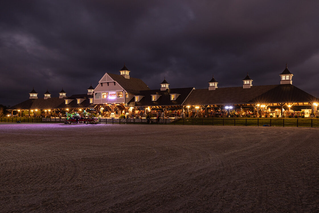 outdoor riding riding sitting beneath the night sky with stables lit up behind it