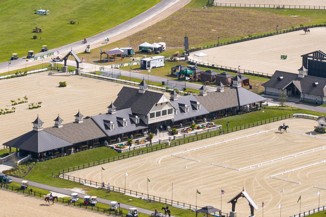 outdoor riding areas at terranova with a facility in the center and a road visible behind it