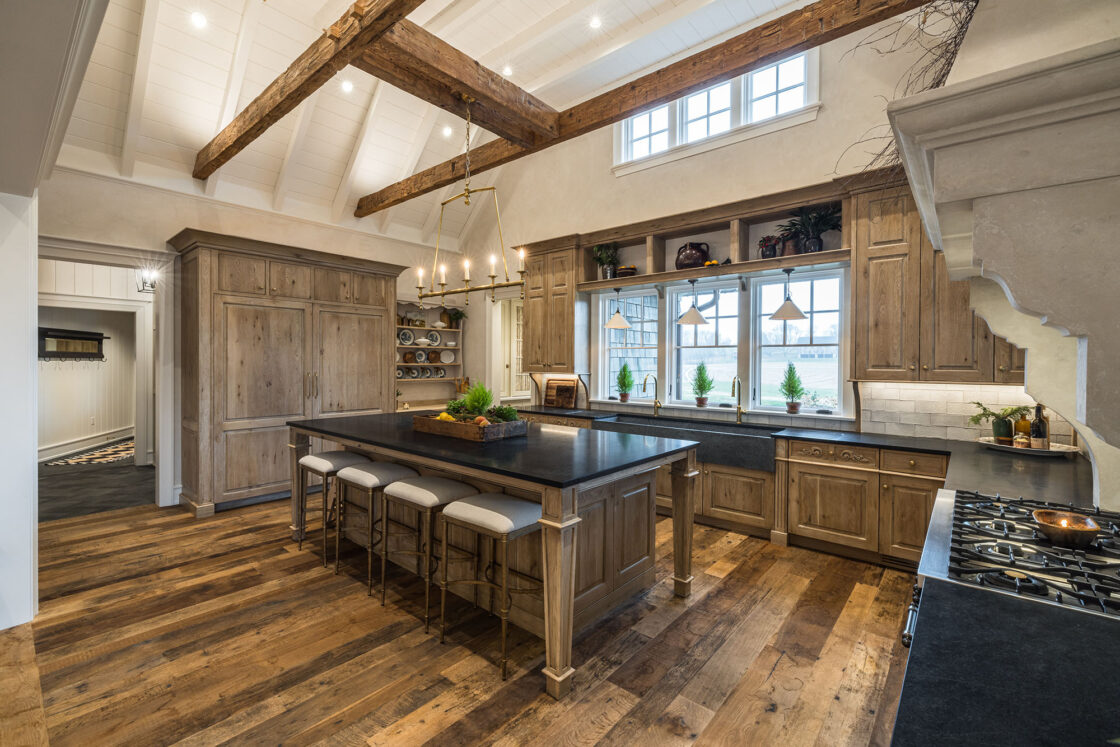 custom luxury home kitchen with hardwood floor which sits beneath a centered island which sits in between a range to the left wooden cabinets to the left and centered