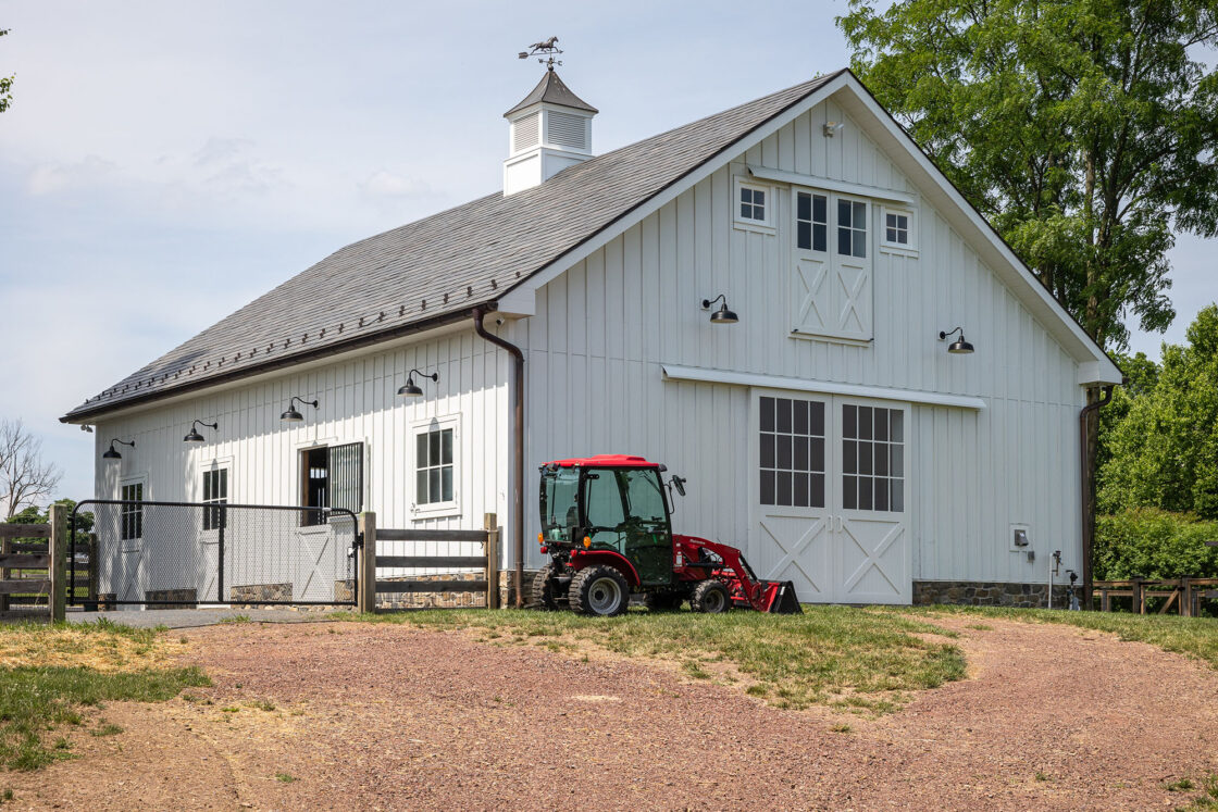 A tractor parked in front of a white barn