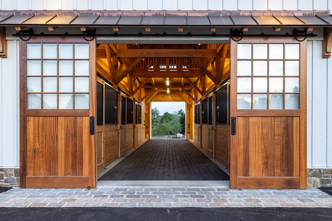 horse stall with open wooden exterior doors and six stalls visible on the inside