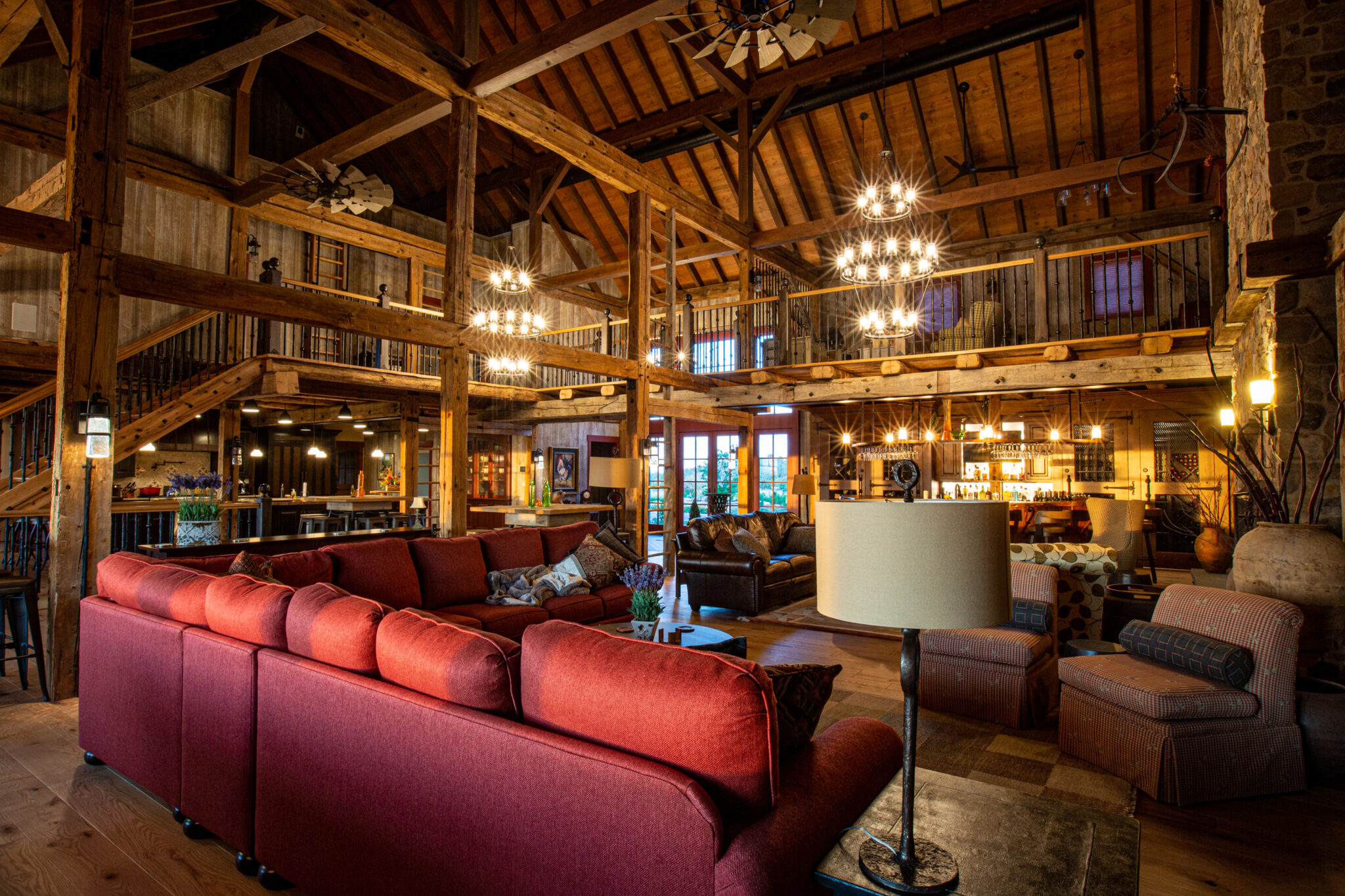 What Makes Timber Ideal for Luxury Home Builds? luxury home interior with red sectional couch on the front left side with multiple timber beams visible throughout the interior