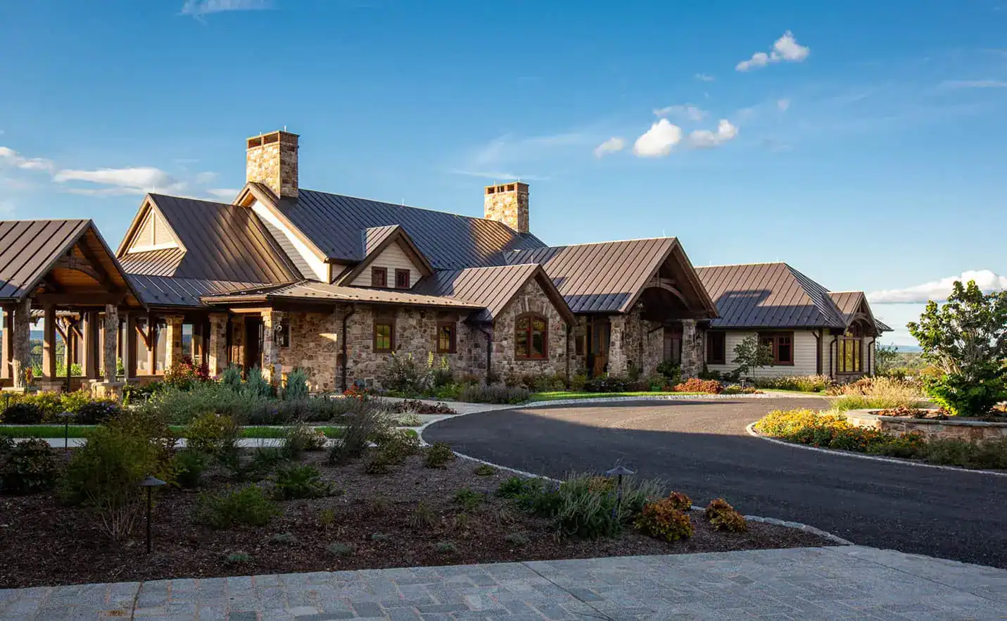 custom luxury home luxury custom structure with dual stone chimneys sitting beneath a clear sky