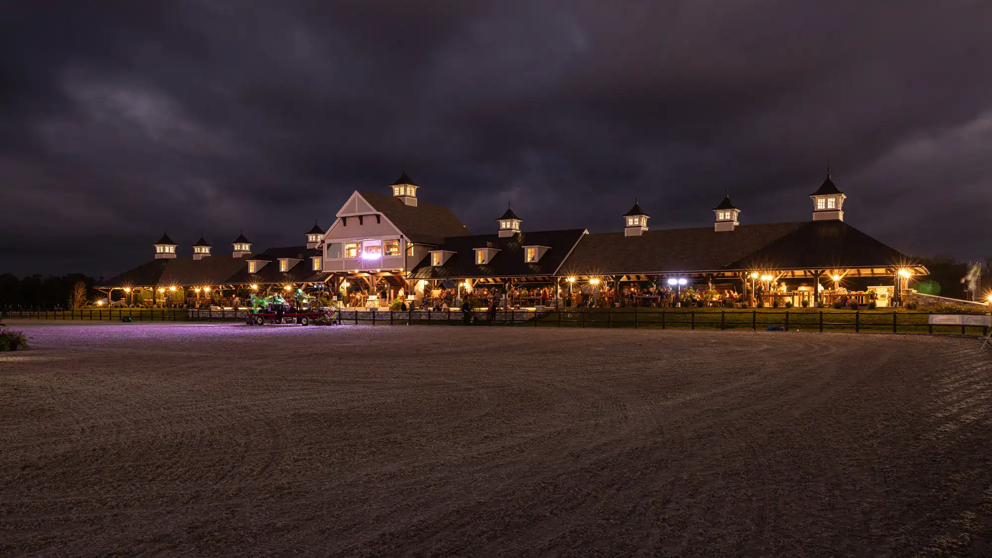 horse riding arena bd outdoor riding arena sitting beneath a night sky with various lights illuminated throughout the property