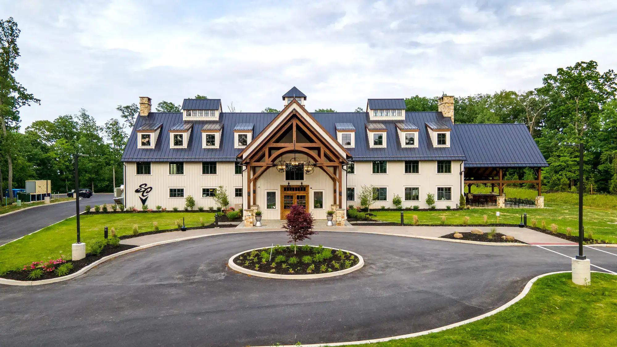 south county brewing south county brewing front entrance sitting beneath a slightly cloudy sky with a circular driveway in front of it