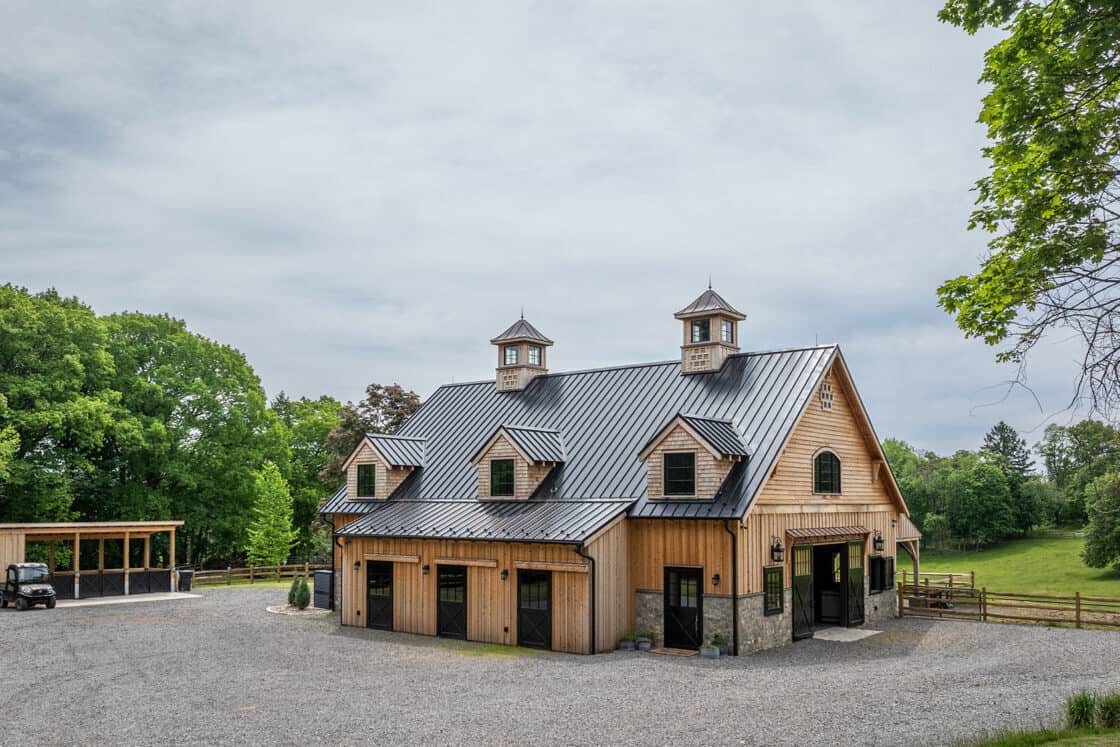 custom horse barn with two cupolas sitting beneath cloudy sky