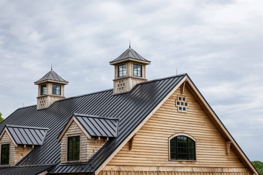 custom barn with two cupolas sitting beneath a cloudy sky